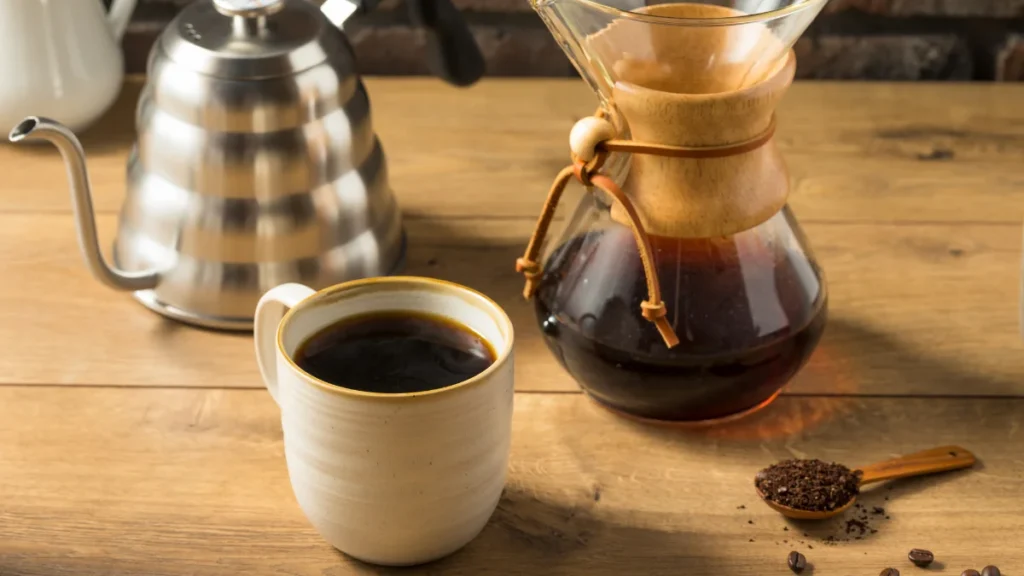 coffee extraction explained: a cup of coffee half-filled pour-over jar and kettle on a table