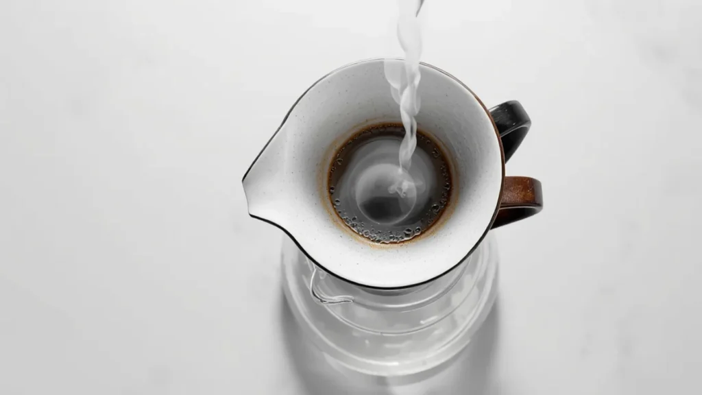 Preheating a ceramic pour over dripper with hot water before brewing to reduce heat loss`